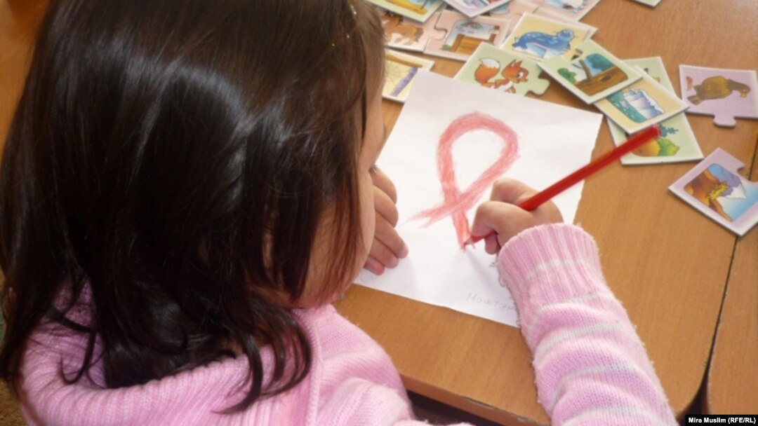 An HIV-infected child draws a Red Ribbon, the international symbol of HIV and AIDS awareness, at the Center for Maternity and Childhood in Shymkent in this 2010 photo.