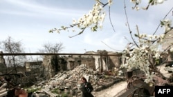 A woman walks past buildings ruined in the August 2008 fighting in South Ossetia's Tskhinvali.