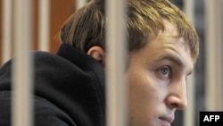 Opposition leader Zmitser Dashkevich sits inside a guarded cage during a court hearing in Minsk on March 22.