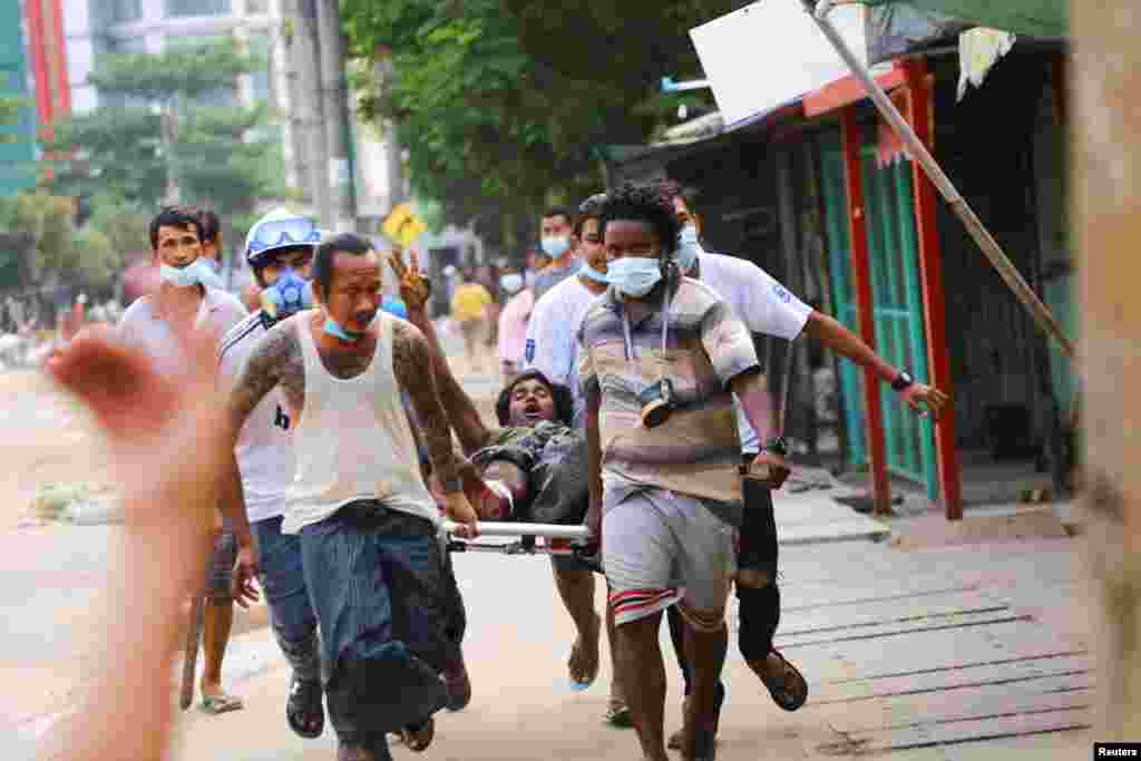 Мужчина на фото салютует привычным для протестующих в Мьянме приветствием. Он получил ранения во время разгона демонстраций, его несут для предоставления медпомощи в районе Тингангюн, Янгон, Мьянма 14 марта 2021
