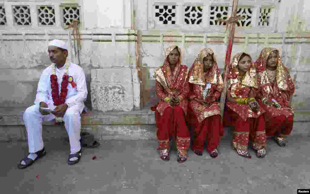 A groom and four brides sit outside the venue of their weddings at a mass Muslim marriage ceremony in the western Indian city of Ahmedabad. (Reuters/Amit Dave)