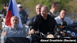 Serghei Aksionov (stânga), alături de Vladimir Putin, la ghidon, în timpul unei manifestații a motocicliștilor „Lupii de noapte” din Crimeea, august 2019.