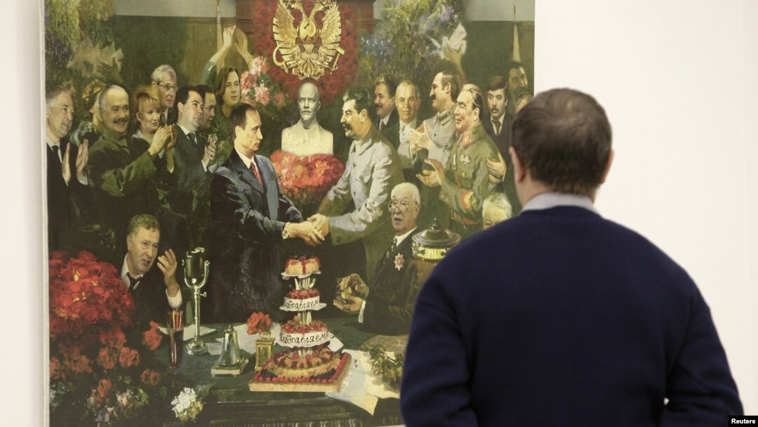 A man looks at a collage by Andrei Budayev showing President Vladimir Putin and Soviet dictator Josef Stalin shaking hands.