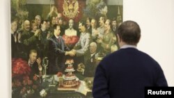 A man looks at a collage by Andrei Budayev showing President Vladimir Putin and Soviet dictator Josef Stalin shaking hands.
