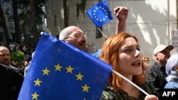 Manifestanți țin steaguri europene în timp ce protestează împotriva proiectului de lege privind „influența străină” în fața clădirii parlamentului din Tbilisi, la 17 aprilie 2024.