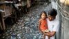 Muškarac nosi djevojčicu duž kanala zagađenog plastikom i otpadom u Manili 22. marta 2019. (Ilustrativna fotografija)