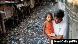 Muškarac nosi djevojčicu duž kanala zagađenog plastikom i otpadom u Manili 22. marta 2019. (Ilustrativna fotografija)