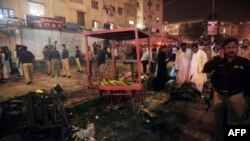 Pakistani security officials scan the site of a bomb blast at a Karachi, which killed at least six people on September 18.