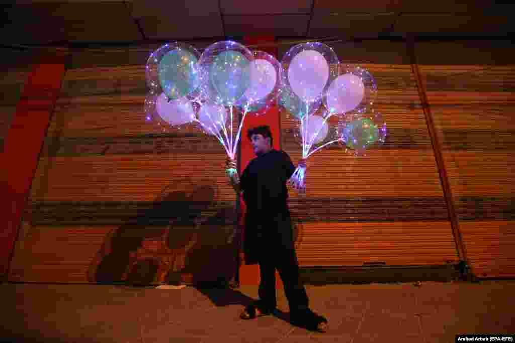 A boy sells balloons in front of a closed market as the government reduces business hours after new cases of COVID-19 were reported across the country, in Peshawar, Pakistan.