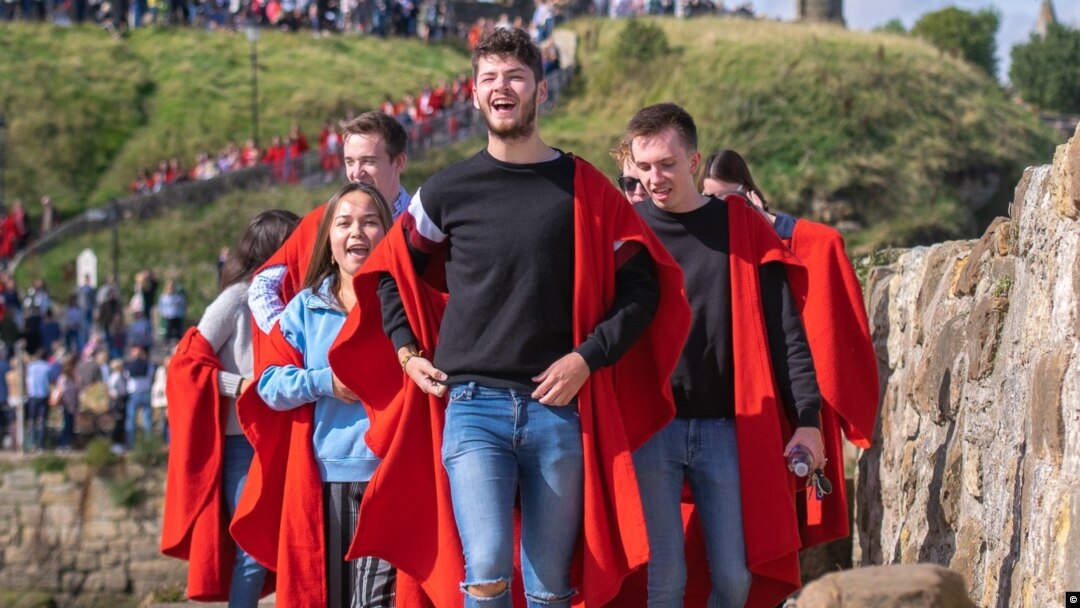 Tradiționala plimbare pe zidul de lângă mare a studenților de la St Andrews Univerity , Scoția, Marea Britanie