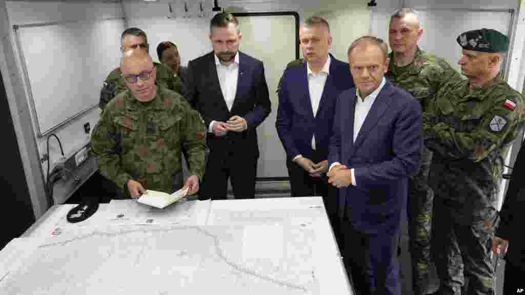 Poljski premijer Donald Tusk (prednji desno), ministar odbrane Wladyslaw Kosiniak-Kamysz (u sredini) i ministar unutrašnjih poslova Tomasz Siemoniak (desno u sredini) u posjeti vojsci u Dubicze Cerkiewni, na istoku Poljske, 29. maja. &quot;Ovdje se ne bavimo (samo) bilo kakvim tražiocima azila, mi se bavimo koordinisanom, vrlo efikasnom na mnogim nivoima, operacijom probijanja poljske granice i pokušajima destabilizacije zemlje&quot;, rekao je Tusk.