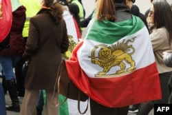 A demonstrator wearing a pre-1979 Iranian flag with the Lion and Sun emblem attends a rally in support of the Iranian people following the killing of Iran's Supreme Leader Ali Khamenei in a joint US-Israeli strike, in Brussels on March 1.