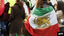 Demonstrantkinja s iranskom zastavu iz perioda pre 1979. s grbom lava i sunca na skupu podrške iranskom narodu posle ubistva iranskog vrhovnog vođe Alija Hamneija u američko-izraelskom napadu, Brisel 1. mart 2026.
