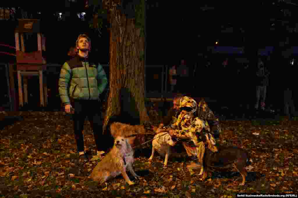 A man with his dogs watches rescue efforts at the site of the Dniprovskiy District strike early on November 25.