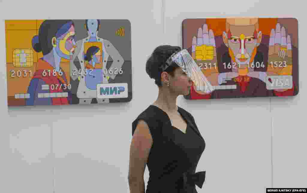 A visitor examines artworks by Dmitri Aske of Russia.