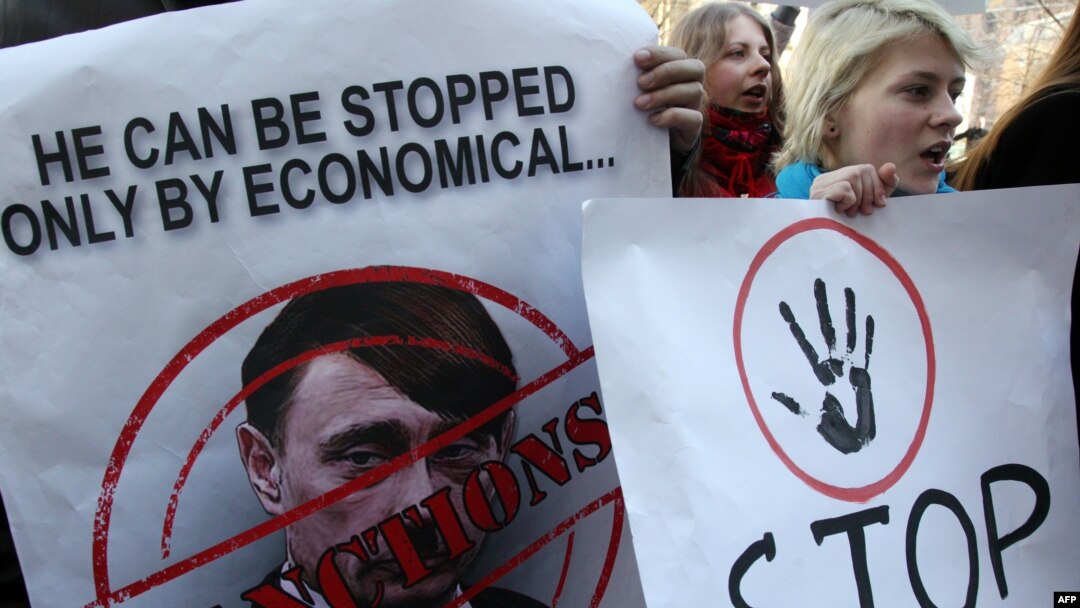 An activist in Kyiv holds a poster of Russian President Vladimir Putin caricatured as Adolf Hitler.