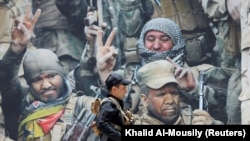 IRAQ -- A members of Iraqi Popular Mobilization Forces (PMF) walks past a poster of PMF members at Popular Mobilization Forces Media Center in Baghdad, Iraq July 2, 2019.