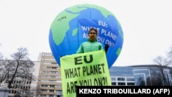 A Greenpeace aktivistája zászlót tart az európai vezetők felszólítására, hogy 2020. december 10-én hozzanak intézkedéseket a környezetvédelem érdekében Brüsszelben