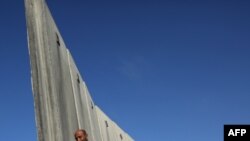 Palestinci šetaju dijelom kontroverzne izraelske razdvajajuće barijere prema kontrolnom punktu Qalandia, da bi prešli sa Zapadne obale u Jeruzalem na molitve u petak u kompleksu džamije Al-Aqsa