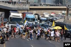 Manifestanții blochează o stradă în timpul protestelor antiguvernamentale, cerând un acord pentru eliberarea israelienilor reținuți în Fâșia Gaza de militanții Hamas. Tel Aviv, pe 17 august 2025.