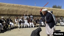 An Afghan judge whips a woman in front of a crowd in Ghor Province in 2015.