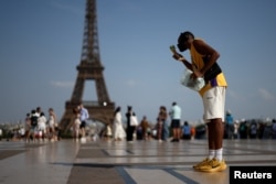 Një person ha akullore përballë Kullës Eifel gjatë valës së të nxehtit në Paris, Francë, më 27 qershor 2026.