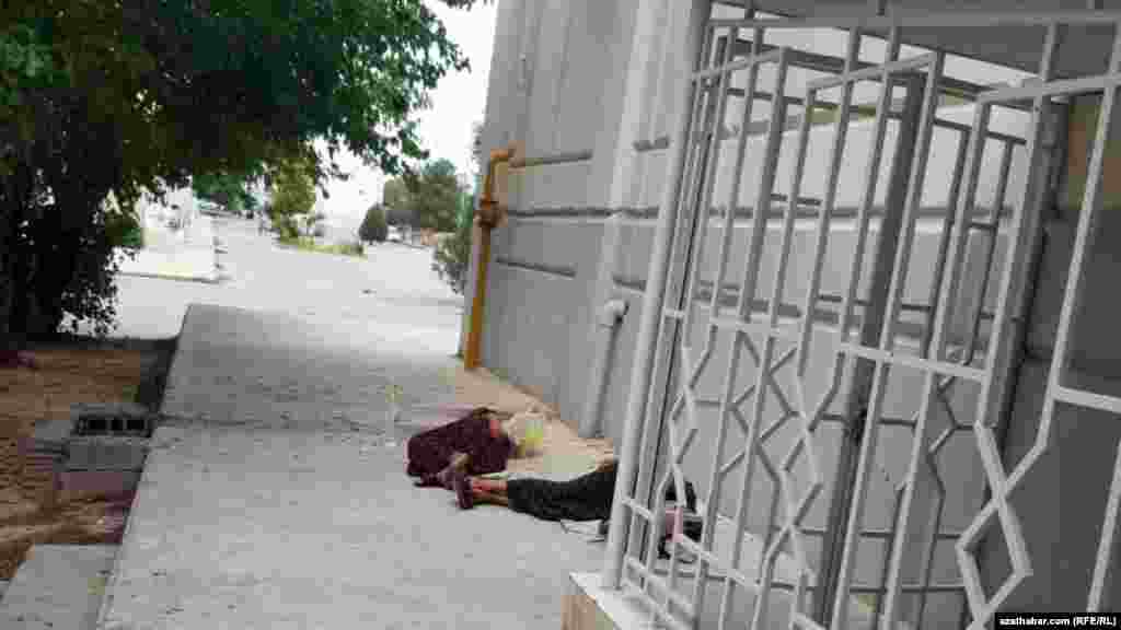 Aşgabat. Tomsuň tüp syssysynda daşarda işläp, dynç almaga oturan tämizlik işgärleri. Iýul, 2021.&nbsp;