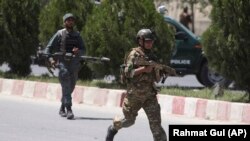 Afghan security personnel get into position at the site of an attack on the Interior Ministry in Kabul on May 30. 