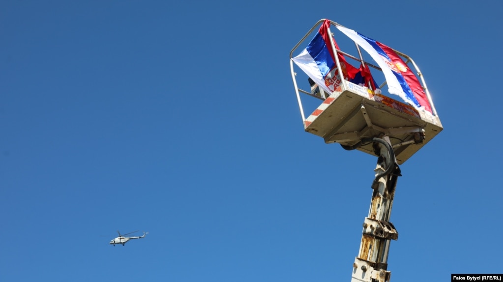 A NATO helicopter flies over a Serbian flag in Jarinje.