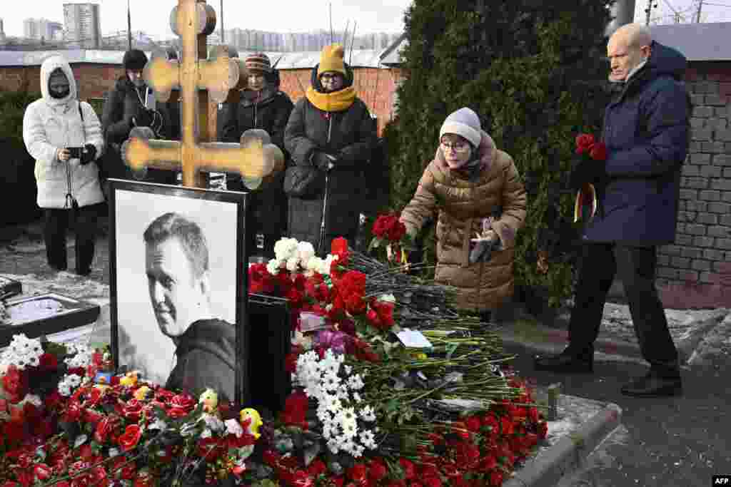 People lay flowers at the grave of Russian opposition leader Alexei Navalny at the Borisovo cemetery in Moscow on February 16, 2025, marking the first anniversary of his death in an Arctic colony under murky circumstances.