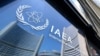 (FILES) Buildings of the International Atomic Energy Agency (IAEA) headquarters reflect in doors with the agency's logo during the IAEA’s Board of Governors meeting in Vienna, Austria on June 13, 2025, where the IAEA’s head Rafael Grossi briefed board mem