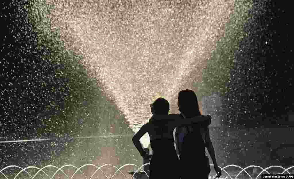 Two girls pass by a fountain in downtown Bucharest, Romania.&nbsp;