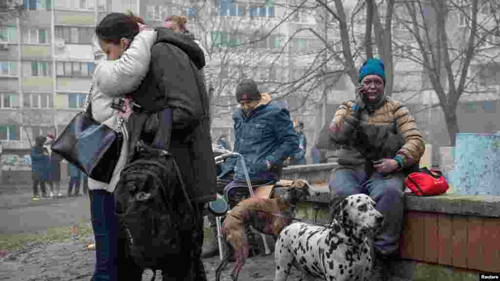 Residents of a heavily damaged 18-story apartment building gather outside following a Russian missile strike in Kyiv and other regions on February 7 that killed at least five civilians and injured dozens of others, including a pregnant woman.
