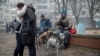 Locuitorii unui bloc de apartamente de 18 etaje din Kiev, grav avariat de atacurile rusești, stau într-un parc, 7 februarie 2024.