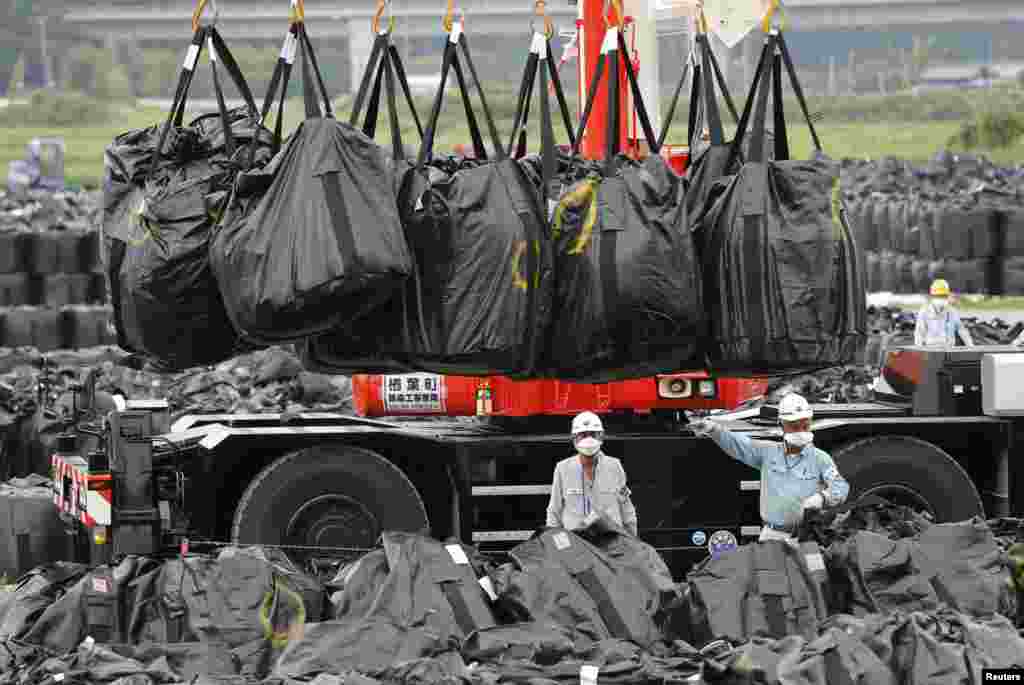 Workers move bags of contaminated soil and debris to a storage site in Naraha.