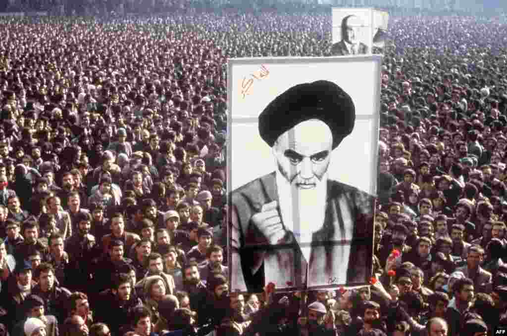 Протесты против шаха продолжали нарастать. Демонстранты держат плакат аятоллы Рухоллы Хомейни во время массовых акций протеста 1 января 1979 года. Хомейни провел 14 лет в изгнании. Кассеты с речами 76-летнего Хомейни были ввезены контрабандой в страну, что вызвало волнения.