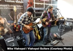 Chitaristul Joe Berger (dreapta) testează o chitară marca Vlahopol Guitars la târgul NAMM de la Los Angeles.