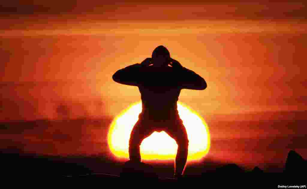 Фізычныя практыкаваньні падчас заходу сонца над узьбярэжжам Фінскай затокі ў Санкт-Пецярбургу, Расея. (AP/Dmitri Lovetsky)
