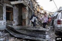 Two woman leave a two-story residential building destroyed in Russian drone attack on Odesa on April 24.