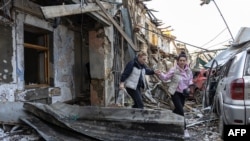 Dvije žene napuštaju dvospratnu stambenu zgradu uništenu u ruskom napadu dronom na Odesu, 24. aprila.