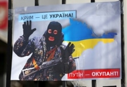 Плакат с изображением президента России Владимира Путина во время акции «Крым – это Украина» у российского посольства в Киеве, 16 марта 2020 года
