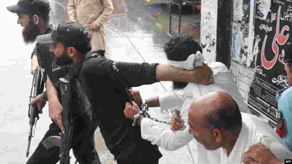 A Pakistani policeman reprimands Islamic cleric Hafiz Khalid Chishti (handcuffed) after he attempted to shout slogans upon his arrival at a court in Islamabad. (AFP/Farooq Naeem)