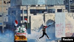 A demonstrator throws away a tear gas canister during an anti-government protests in Baghdad, Iraq November 1, 2019. 