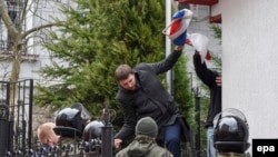 Volodymyr Parasyuk, a former Maidan activist and current lawmaker, tears away a Russian flag from the Russian Consulate during a rally in Lviv on March 9.