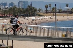 Një person me biçikletë kalon pranë plazhit në Barcelonë të Spanjës më 30 korrik, 2020.