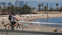 Велосипедист в маске проезжает мимо пляжа в Барселоне, Испания. 30 июля 2020 года.