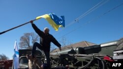 A pro-Russian protester takes down a Ukrainian flag as a group of some 200 protesters storm a Ukrainian air base in the small city of Novofedorivka in western Crimea on March 22.