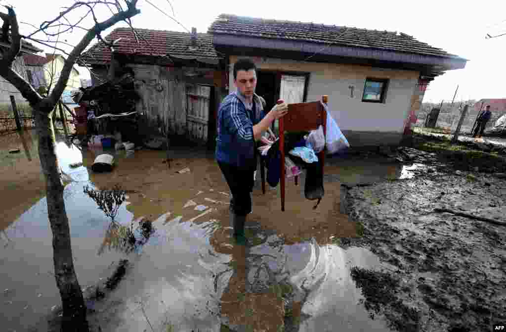 Македония астанасы Скопьеден 60 километр жерде орналасқан Свети Николе қалашығындағы су тасқынынан кейін үйіндегі заттарын сыртқа шығарып жатқан тұрғын. (AFP/Robert Atanasovski)