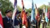 Под звуки оркестра за мемориалом в память погибших во Второй мировой войне ровным рядом выстроились пожилые британские ветераны со знаменами в руках. У нескольких на груди российский триколор