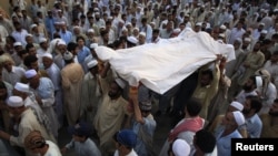 Pakistanis carry the draped body of a suicide-bomb victim to his grave in Pabbi, east of Peshawar, on July 26.